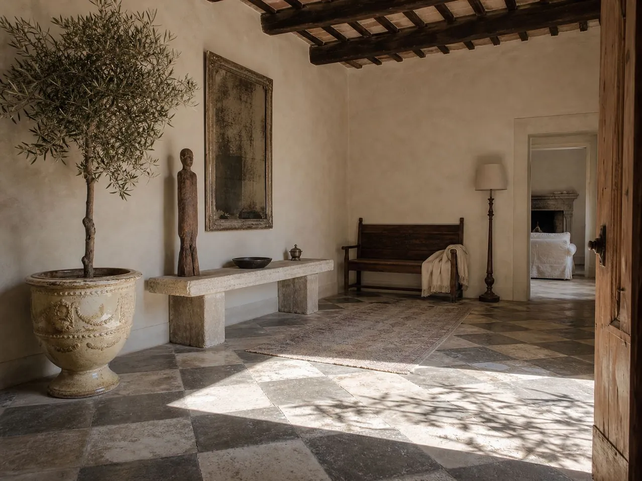 Entrance hall with chequerboard stone floor, a potted olive tree in a classical urn and a carved standing figure — Private Residence, Tuscany